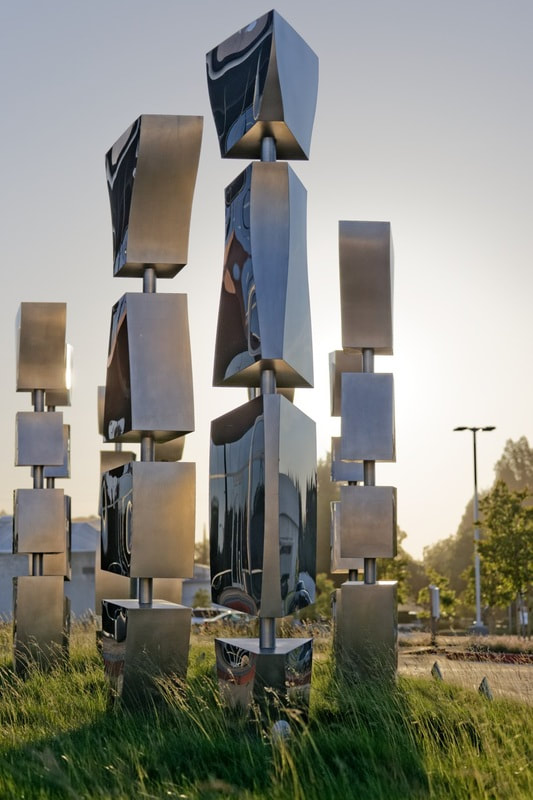 series of polished stainless steel public sculptures in grassy park