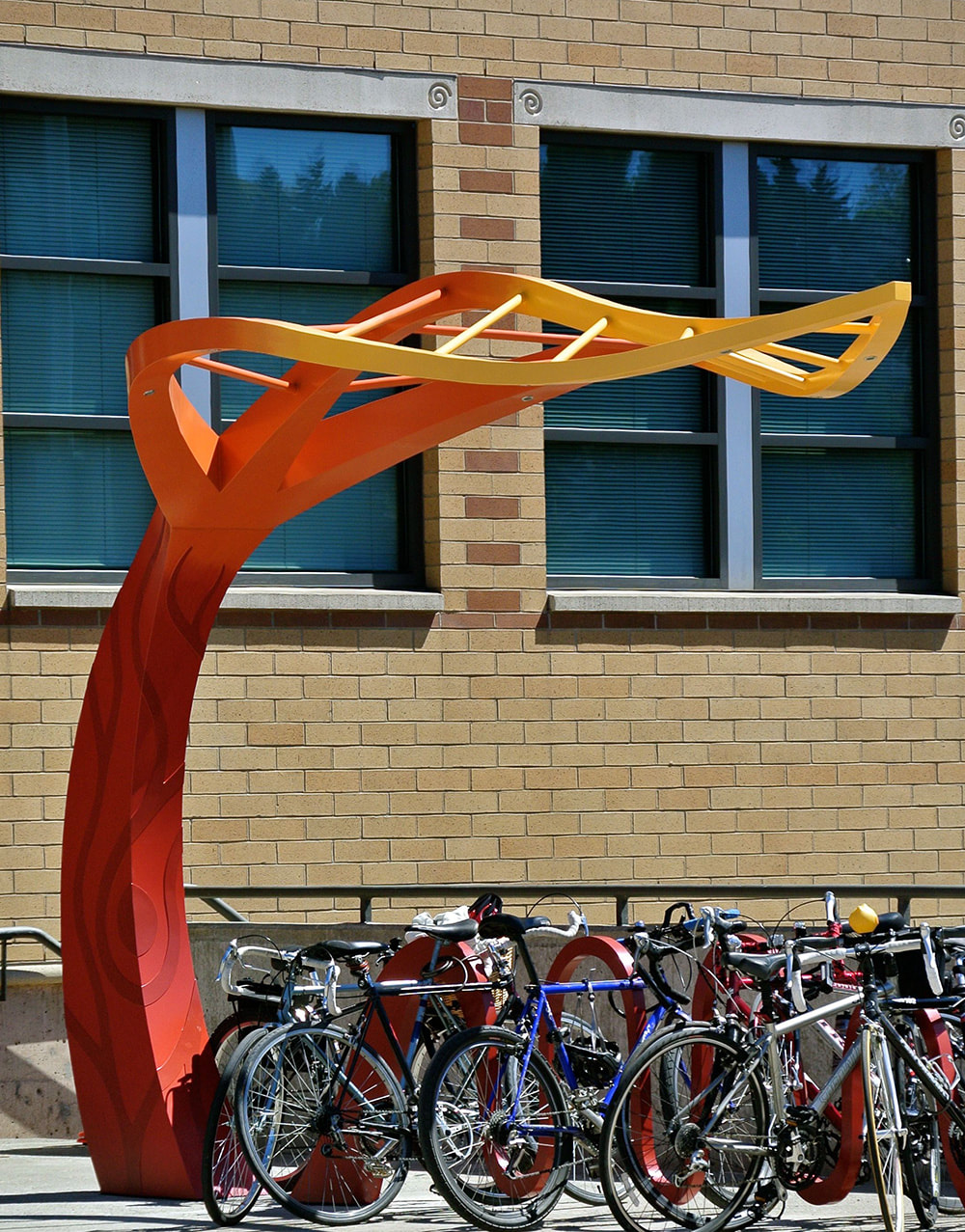 large public art sculpture shaped like a leaf that has a bike rack below it