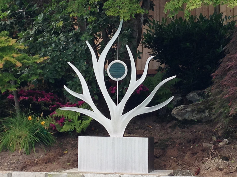 silver coral shaped sculpture with garden background