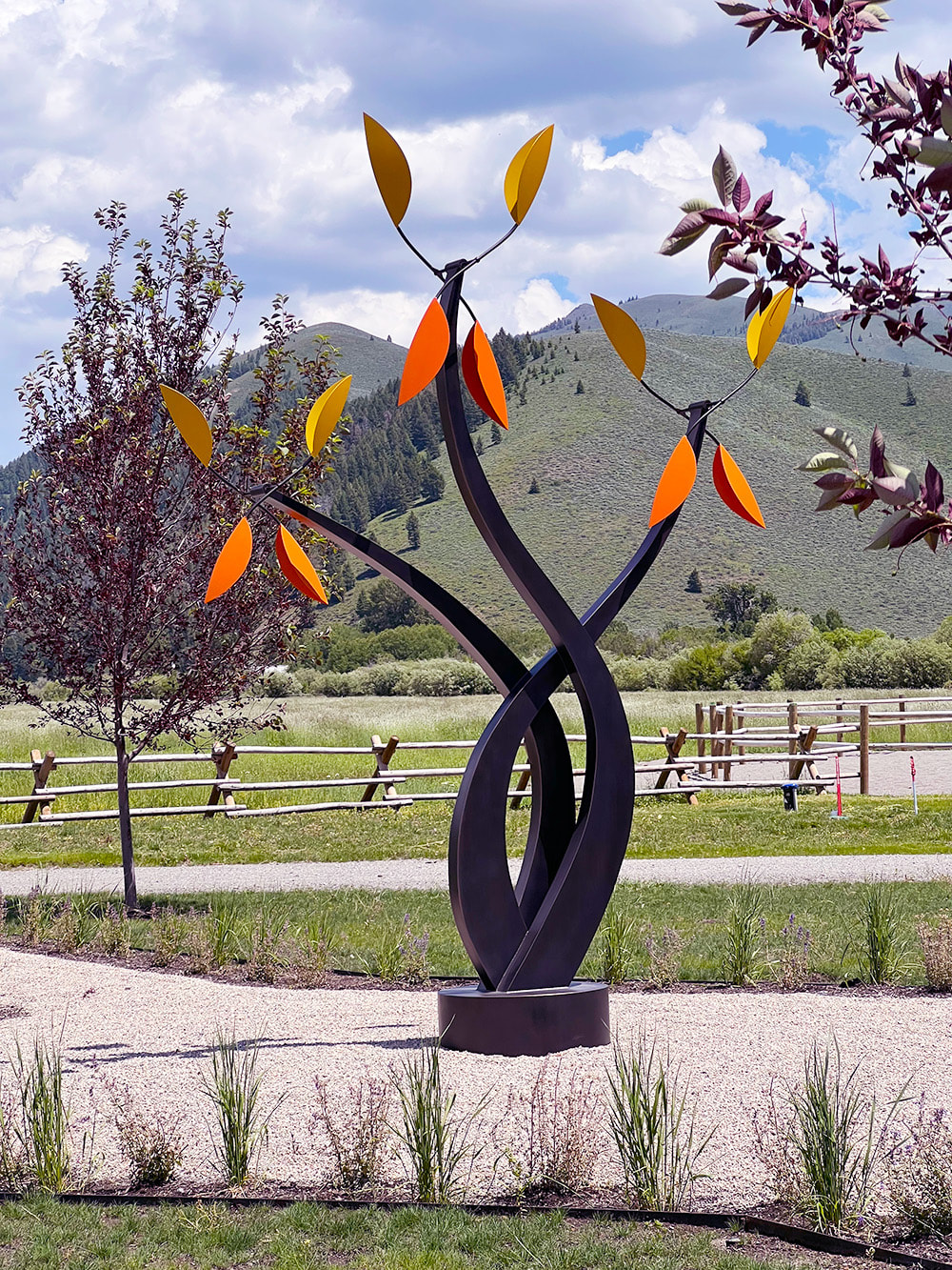 large bronze kinetic sculpture with yellow and orange leaves in a ranch landscape